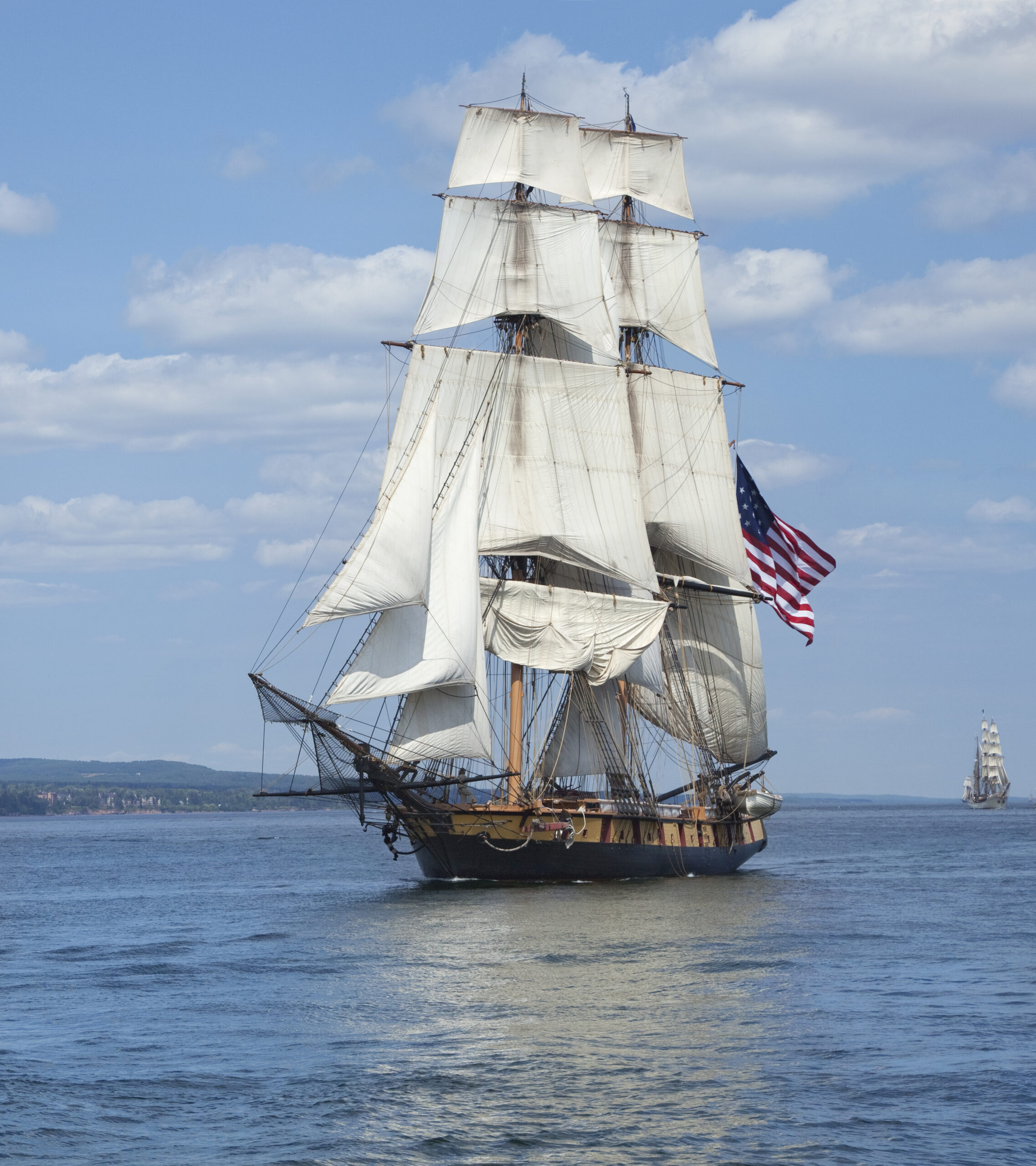 A tall ship sailing with the American flag