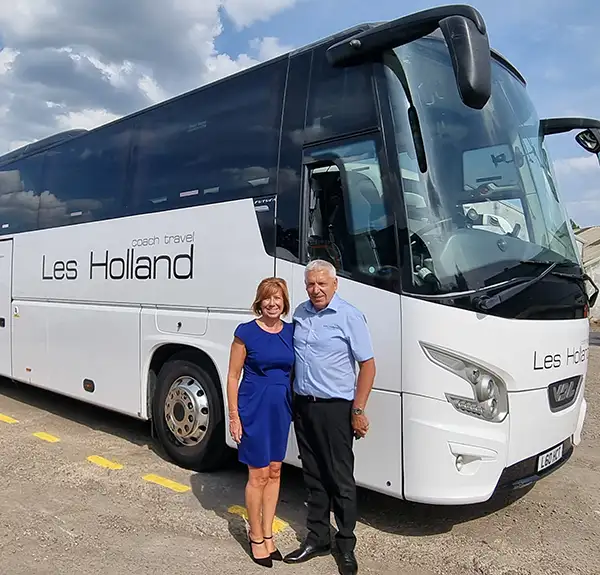 Les and Joanne Holland, owners of Les Holland Coach Travel in front of one of their coaches