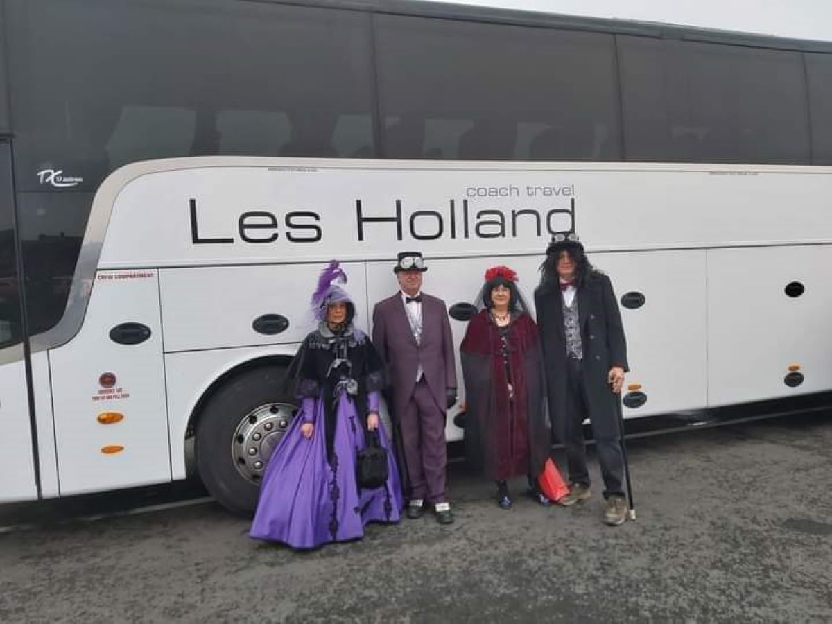 Passengers in fancy dress standing in front of a Les Holland coach
